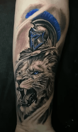 Custom realistic tattoo blending a roaring lion and Spartan helmet with blue highlights, crafted by Elvis Tattoo Shop.